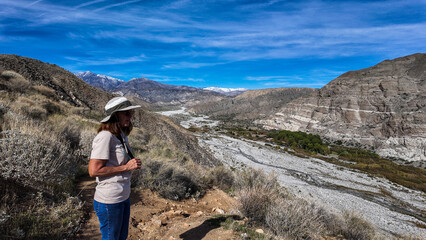 Fototapeta premium The California Whitewater Canyon near Palm Spring with water flowing from the San Gabriel Mountains where frequent flooding occurs with a woman geoloigist evaluating the flood plain.