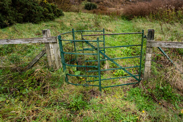 Iron kissing gate, entrance exit gate, in wood fence to access public land in Tarbert, Outer Hebrides, Scotland, UK

