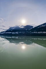Serene Riverside Landscape With Snowy Mountains And Calm Green Waters In British Columbia, Canada Scenery