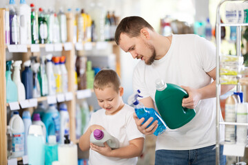 Fototapeta premium Young man with boy shoppers buying laundry detergent in household chemicals store