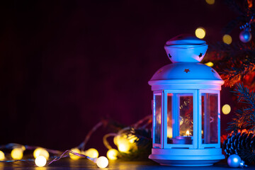 Christmas lantern at night on the table with Christmas tree branches, garland and copy space