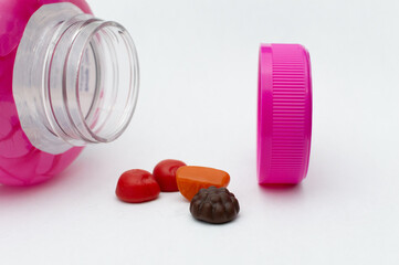 Women&rsquo;s Multivitamins with Pink Bottle on White Background. Close-Up of Women&rsquo;s Multivitamins and Pink Bottle