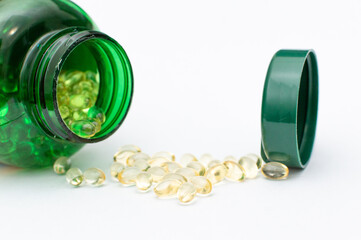 Vitamin D Capsules with Green Bottle on White Background. Vitamin D Pills Spilled from Green Container