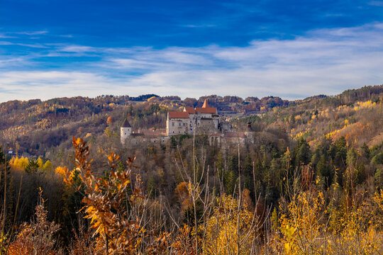 European castle in autumn. Historic stone architecture colorful foliage warm sunlight scenic landscape representing heritage culture seasonal nature scenery and traditional landmark. Hrad Pernstejn