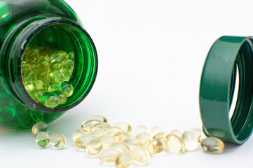 Vitamin D Capsules with Green Bottle on White Background. Vitamin D Pills Spilled from Green Container