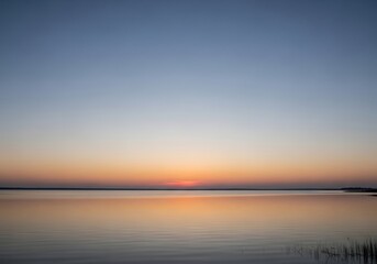 Naklejka premium Tranquil water reflection captures the peaceful sunset in a serene scene