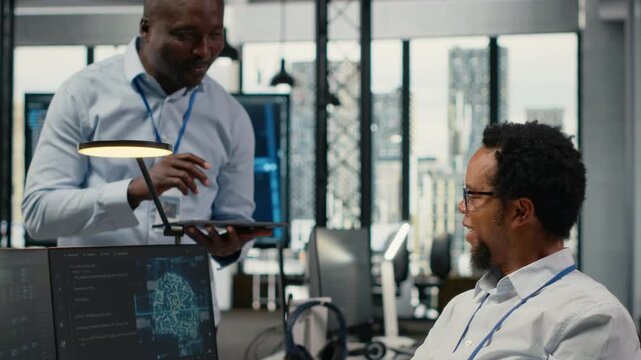 Smiling IT staff members in office using AI to optimize company systems performance. Happy colleagues in startup office use artificial intelligence technology to automate tasks, camera B