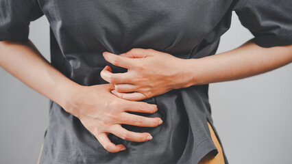 Close-up of a woman clutching her stomach with both hands, depicting abdominal pain or discomfort, ideal for health and medical-related content.