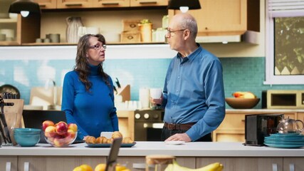 Senior couple standing in home kitchen with coffee and joyful smiles, enjoying casual housework and healthy food moments. Peaceful lifestyle, domestic routine and satisfied living. Camera B. - Powered by Adobe