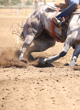 A horse and rider galloping with dirt flying everywhere. This is a photo in a vertical presentation.  A barrel racing event.