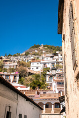Paisaje de Taxco con casas coloniales y el Cristo en la montaña en un día soleado, creando una atmósfera ideal para vacaciones de Año Nuevo.