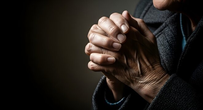 Close-up of older adult hands clasped in silent prayer, embodying a profound spiritual contemplation concept with an emotional dark background - Powered by Adobe