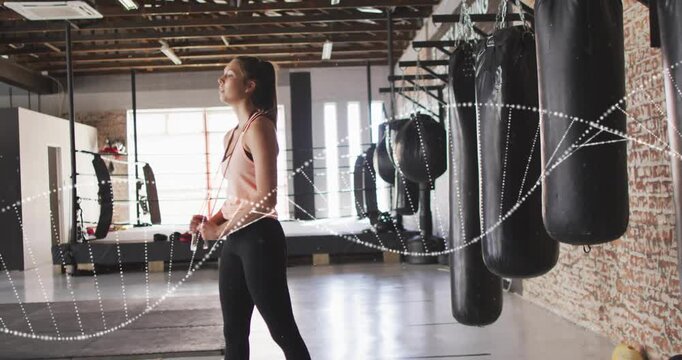 Fit trainee stepping, twisting bottle cap while preparing boxing near heavy bags, particles moving
