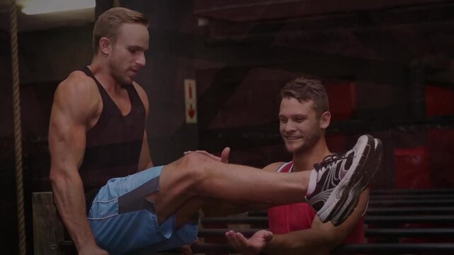 Lifter gripping parallel bars, doing leg raise while spotter supporting calves, building strength
