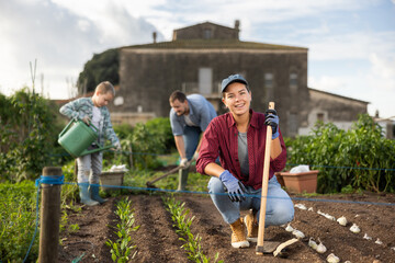Fototapeta premium woman farmer with a garden tool near growing seeds. Planting seeds and fertilizing the land on the farm. A farmer and his family grow organic berries and vegetables