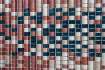 Abstract Checkerboard Wall Design Featuring Alternating Red, Beige Bricks and Reflective Blue-Green Glass Blocks