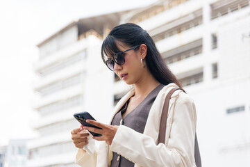 Fototapeta premium Business woman, person, navigates urban street outdoor among people, engaged in work lifestyle checking smartphone, travel background