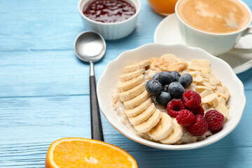 Healthy breakfast. Oatmeal with nuts, banana and berries on light blue wooden table, closeup. Space for text
