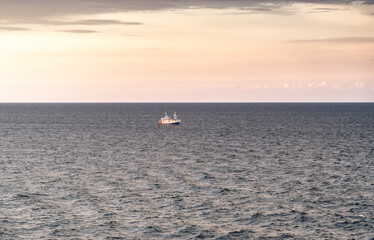 Sunrise breaks over the Skagerrak North Sea in Sweden. A lone shrimp trawler appears on the water, fishing near the coast between Norway and Sweden