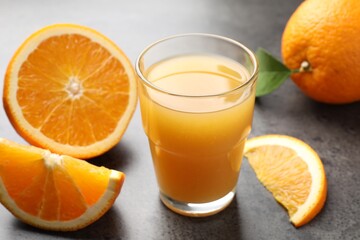 Fresh orange juice and fruits on grey table, closeup