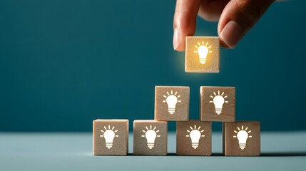 Human hand places the culminating illuminated block representing a final brilliant concept atop a stack of foundational ideas