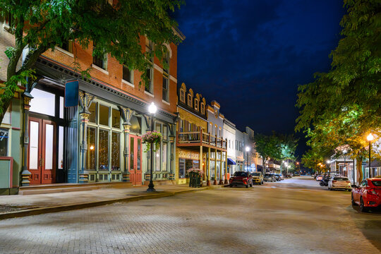Early American buildings with shops and boutiques line the brick paved Main Street in the historic small town of St. Charles Missouri at night. - Powered by Adobe