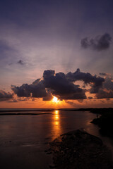 Stunning Sunset Over Calm Ocean With Silhouetted Shoreline, Dramatic Clouds, And Dusk Light