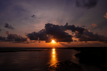 Stunning Sunset Over Calm Ocean With Silhouetted Shoreline, Dramatic Clouds, And Dusk Light