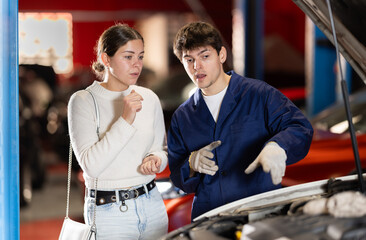 Auto mechanic checking young woman client car in car service center