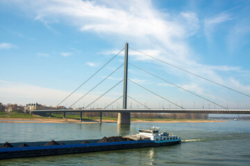 Cargo Ship Passing Under Modern Cable-Stayed Bridge on Rhine River in Düsseldorf