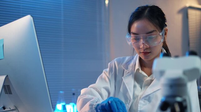 Young asian microbiologist woman working with a test tube, performing medical research for a vaccine in a modern science laboratory