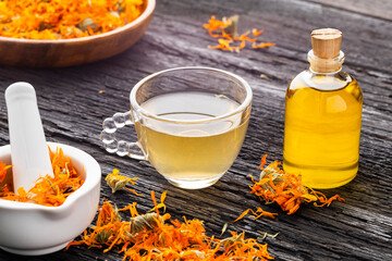 Calendula infusion, dried flowers, and a bottle of herbal oil - Calendula officinalis