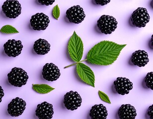 Flat lay of fresh, dark blackberries with scattered green leaves on pastel purple