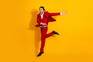 Energetic man in red suit leaps against bold yellow background for a vibrant fashion moment suitable for advertising campaigns