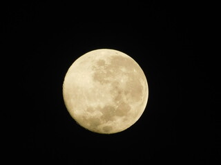 Detailed close-up view of a yellow waxing crescent moon with visible craters against a dark black sky
