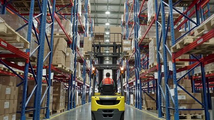 warehouse worker operating forklift moving stacked boxes on pallet | logistics, industry, warehouse, transportation, commerce theme - Powered by Adobe