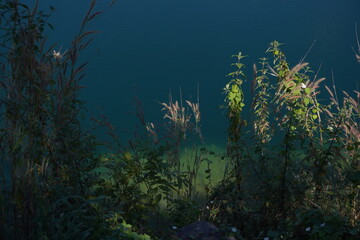 Fototapeta premium Blue Lagoon Phuman Khon Kaen: Majestic gray limestone cliff beside a clear turquoise water pond, with perfect reflection under the summer sky