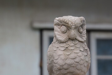 Stone Owl Sculpture with Intricate Feather Details Against a Blurred Background