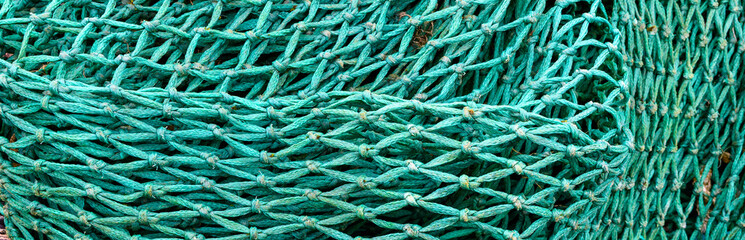 Closeup of pile of blue green industrial grade fishing nets, commercial fishing industry, storage...