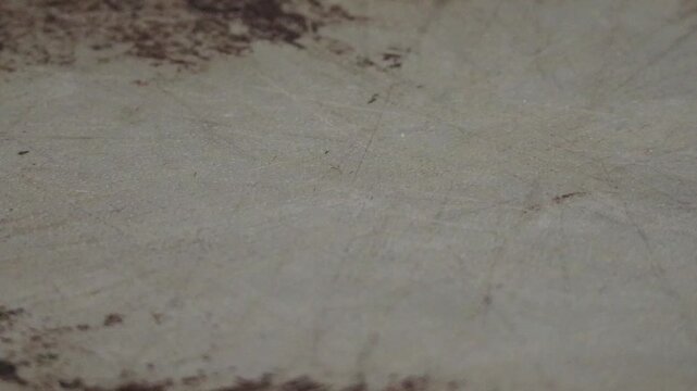 An extreme close up of non stick spray being sprayed onto a well worn baking sheet.