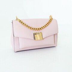 Light soft pink women's handbag on a white background. Stylish accessories and clothes