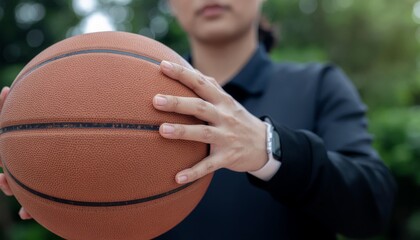 Woman holding basketball with both hands outdoors.