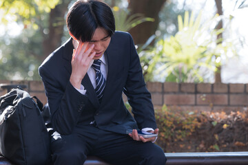 外回りの営業でベンチに座って悩む男性ビジネスマン　営業成果が未達で困る頭を抱える