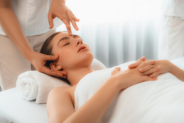 Caucasian woman enjoying relaxing anti-stress head massage and pampering facial beauty skin recreation leisure in dayspa modern light ambient at luxury resort or hotel spa salon. Quiescent