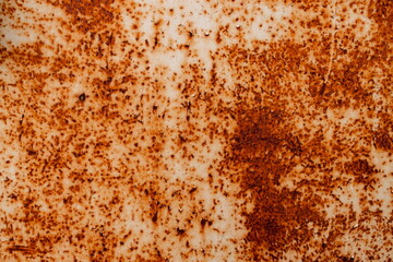 Metal surface shows rust spots with orange and brown colors in close-up view, indicating age and wear over time in an industrial setting