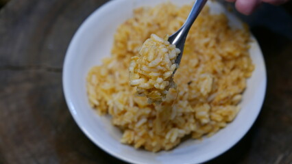 Close-up shot: someone eating risotto with a fork. A plate of risotto on the table. A rice bowl.