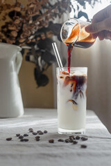 iced latte coffee on table, Espresso coffee is being poured into a glass filled with milk and ice.