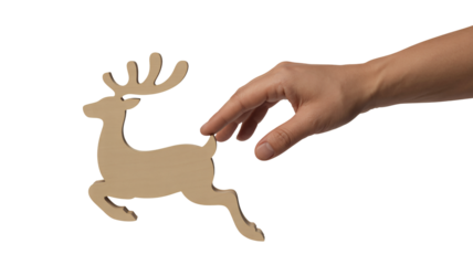 Hand reaching out to touch a small wooden reindeer cutout against a stark for crafting