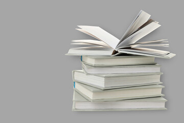 An open book is on top of several closed books with blank pages