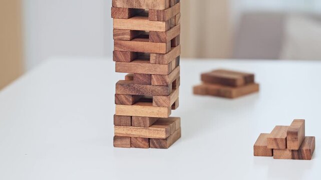 Asian wooden block game tower strategy hand removing block family play table casual careful hand move playful concentration wooden block tower game block stacking strategy family play table hand